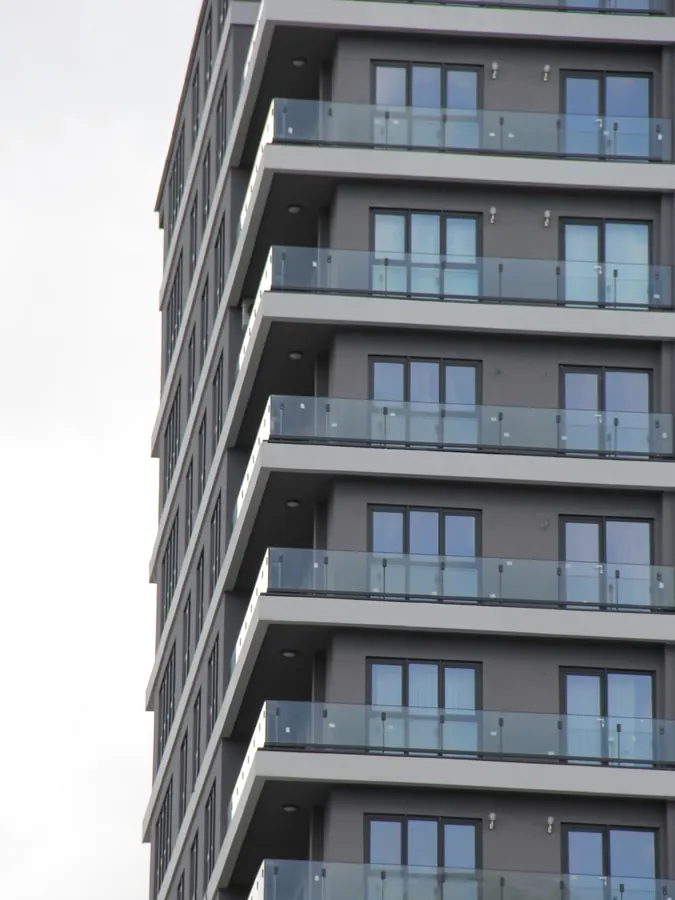 Edifício alto visto de baixo, com varandas em guarda-corpo de vidro