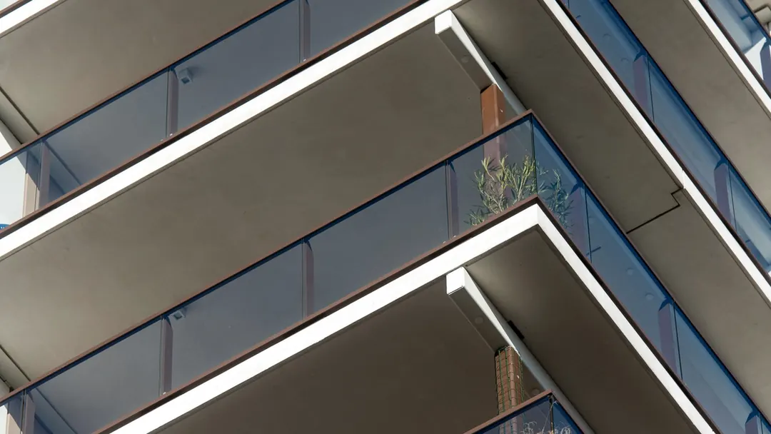 Varandas sobrepostas de um edifício com guarda-corpos de vidro