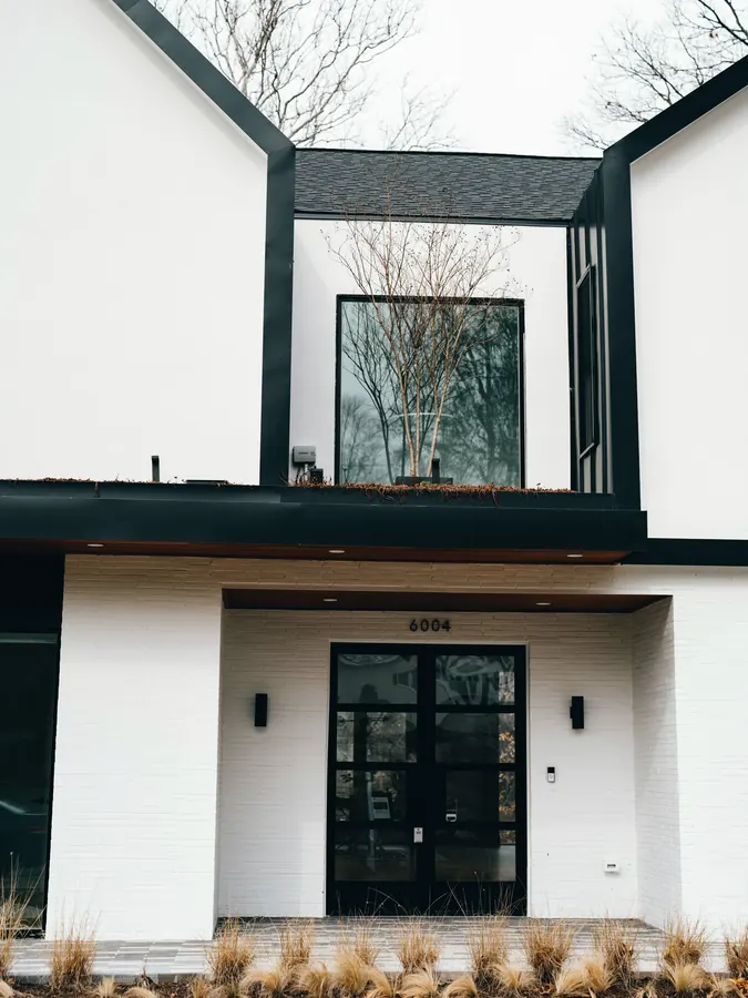 Casa branca com porta de entrada em vidro e perfil preto