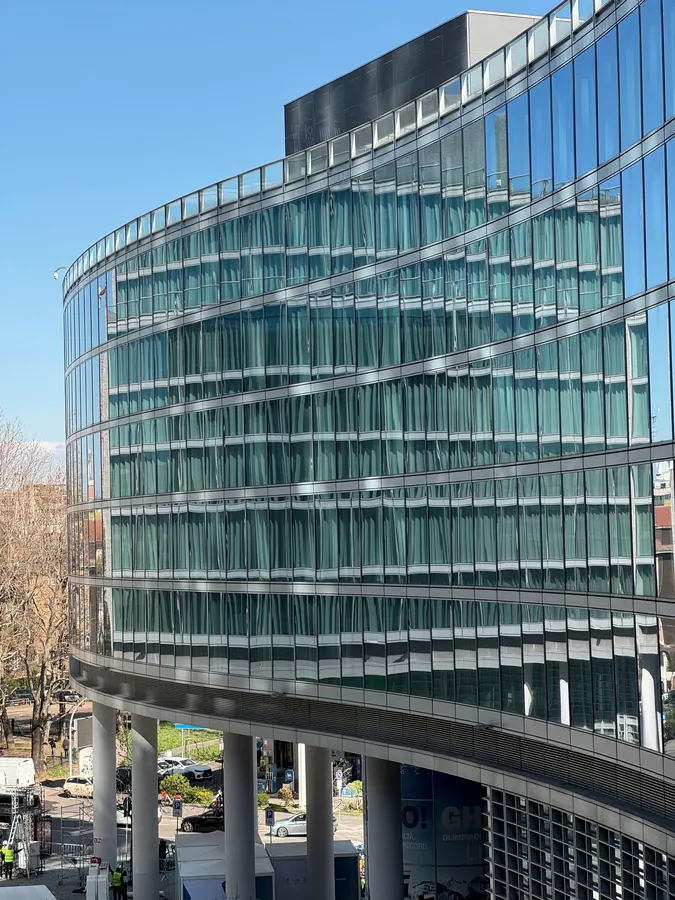 Fachada curva de vidro com faixas horizontais de alumínio, vista de baixo
